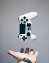 A game console controller hovering above a hand.